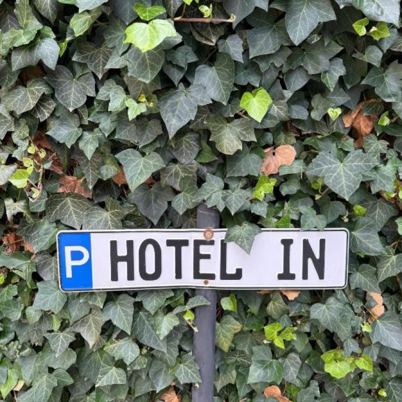 Hinweisschild zum Parkplatz des Hotel In an einer begrünten Wand