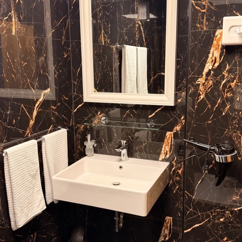 Waschbecken mit beleuchtetem Spiegel, Handtüchern und Föhn im Bad des Doppelzimmers im Hotel In Amberg